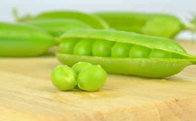 Fresh wet peas and pea pod on a wooden board