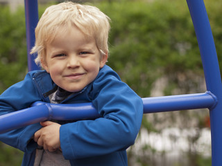 four year old boy at the playground smiling into camera