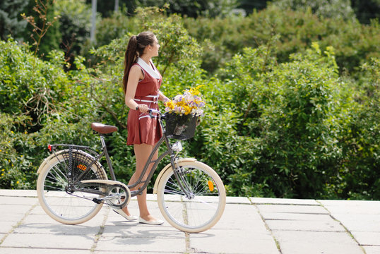 young pretty woman with bicycle and flowers