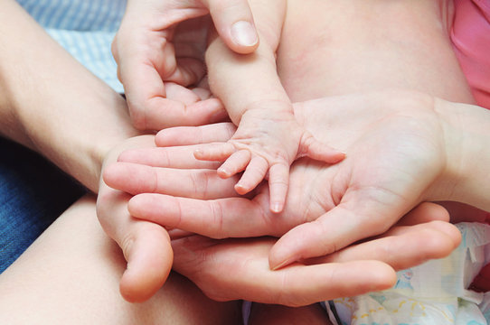 A Mother and Father hold newborn baby hand