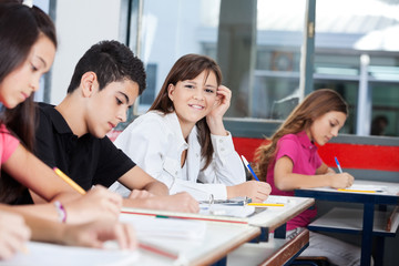 Teenage Girl With Friends Writing At Desk