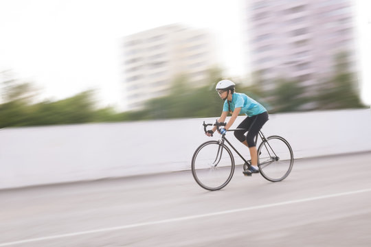 young female athlete racing on a bike. motion blurred image