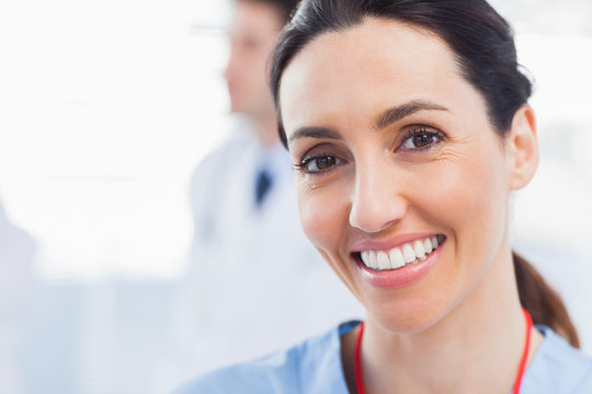 Smiling nurse looking at camera with a doctor behind her