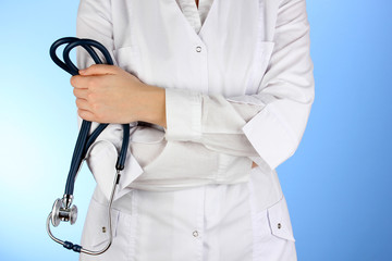 Doctor with stethoscope in hands on blue background