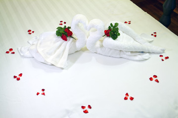 Close up of two nice towels swans on white bed sheet