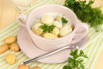 Tender young potatoes with sour cream and herbs in pan