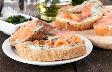 Fish sandwiches on cutting board and plate on wooden table