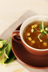 Cup of tea with linden on napkin   wooden table
