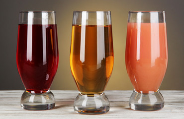 Glasses of fresh juice on table on gray background