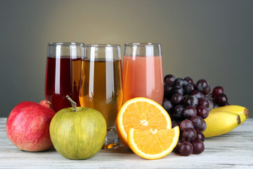 Glasses of fresh juice on table on gray background
