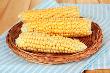 Fresh corn on wicker mat, on wooden background