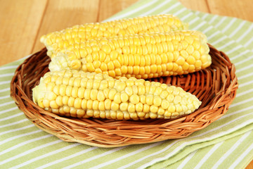 Fresh corn on wicker mat, on wooden background