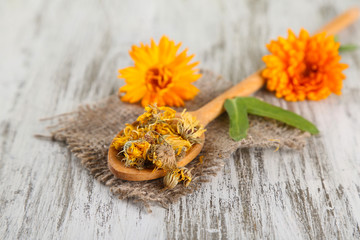 Fresh and dried calendula flowers on wooden background