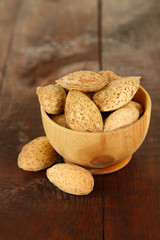 Almond in wooden bowl, on wooden background