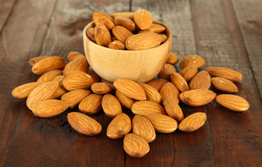 Almond in wooden bowl, on wooden background