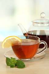 Cup of tea with lemon on table on light background