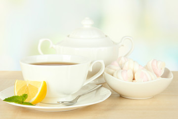 Cup of tea with lemon on table on light background