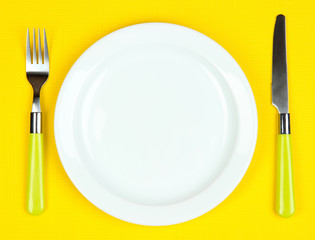 Knife, color plate and fork, on color background