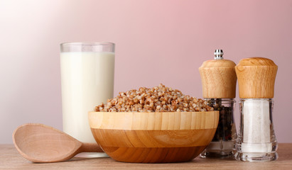 Boiled buckwheat in a wooden bowl with a glass of milk