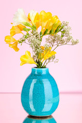 Beautiful bouquet of freesia in vase on pink  background