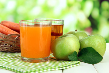 Glasses of juice, apples and carrots