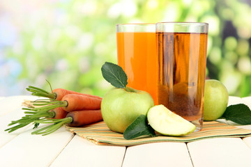 Glasses of juice, apples and carrots