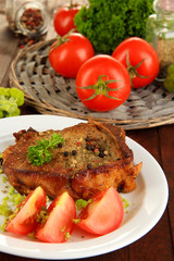 Piece of fried meat on plate on wooden table close-up