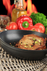 Piece of fried meat on pan on wooden table on fire background