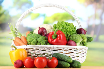 Fresh vegetables in white wicker basket on bright background