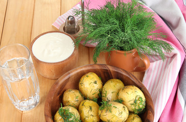 Boiled potatoes on wooden bowl near napkin on wooden table