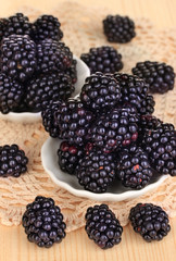 Sweet blackberry in bowls on wooden table