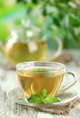 Cup of herbal tea with fresh mint flowers on wooden table