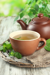 Teapot and cup of herbal tea with fresh mint on wooden table
