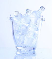 Minibar bottles in bucket with ice cubes, isolated on white