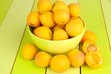 Fresh natural apricot in bowl on green wooden table