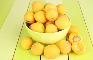 Fresh natural apricot in bowl on green wooden table