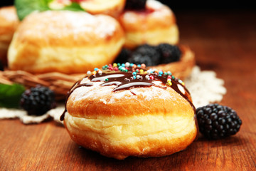 Tasty donuts with chocolate and berries on wooden table