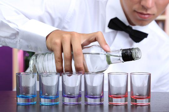 Bartender is pouring  vodka into glasses