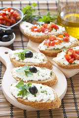 Crostini with cottage cheese, parsley, tomato and olives on cutt