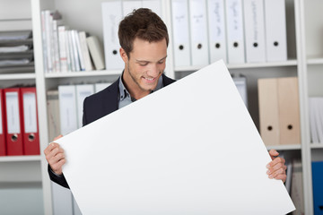 lächelnder mann im büro hält weißes plakat