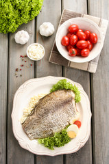Fried cod on white plate with fresh vegetables and egg