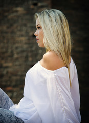 Profile of pretty blonde girl sitting outdoors