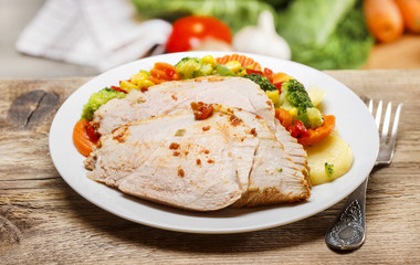 Baked meat with vegetables on wooden table. Fresh raw vegetables
