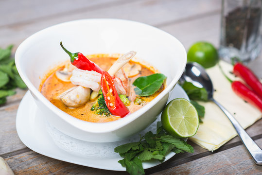Traditional spicy Thai Tom Yam soup on a wooden table