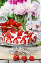 Strawberry cake on rustic wooden table in lush summer garden