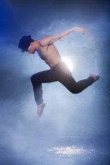 Fototapeta na wymiar Wet dancer. Young male dancer in black fedora dancing on the wet