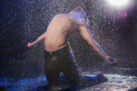 Dancing in the rain. Young male dancer in black fedora dancing u - Powered by Adobe