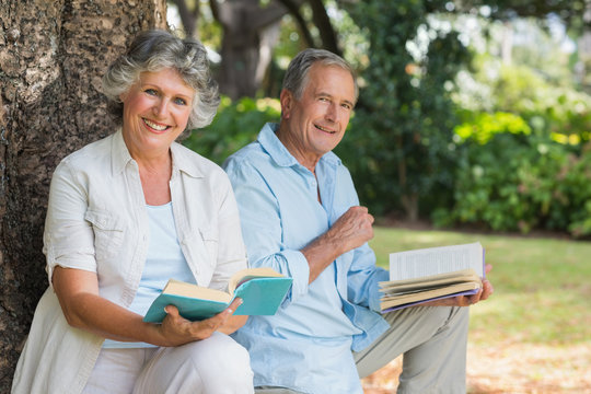 Smiling mature couple reading books together