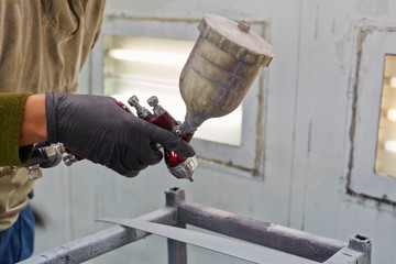 Male hand in glove with spray paint gun, painting car details