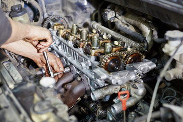 Mechanic hands tighten nut with wrench while repairing engine